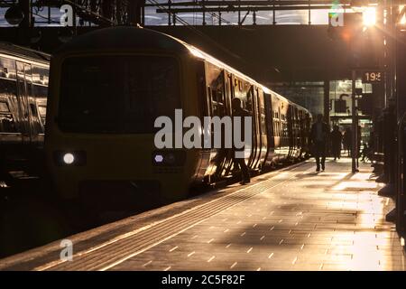 Silhouettes of passengers boarding a Northern rail class 323 electric train at  Manchester Piccadilly railway station on a summer evening Stock Photo