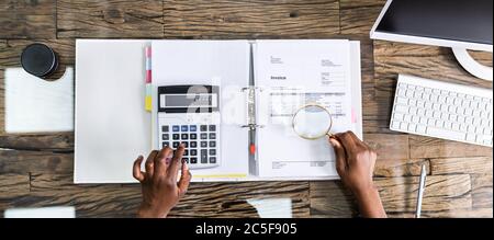 Auditor Investigating Business Fraud Using Magnifying Glass In Office Stock Photo