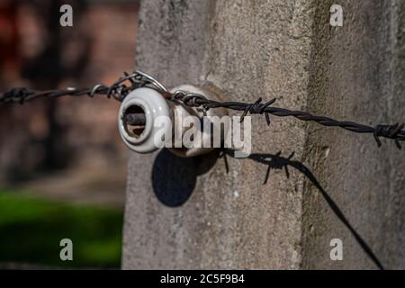 Electric and barbed wire fence in the Concentration Camp Auschwitz. Monument against genocide Stock Photo
