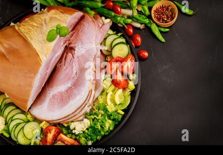 Whole cutted ham with vegetables and green herbs. Stock Photo