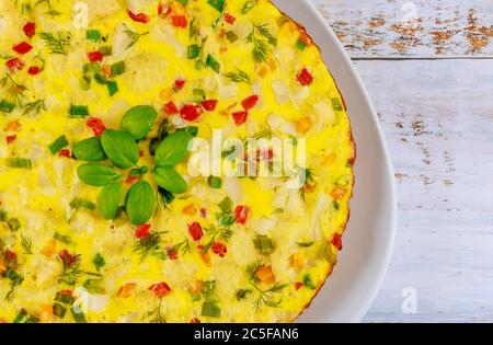 Omelette with chives, bell pepper and cauliflower on white wooden background. Close up. Stock Photo