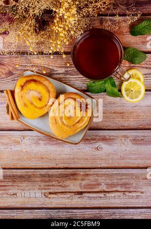 Breakfast with glazed cinnamon rolls and cup of tea with lemon and mint. Top view. Stock Photo