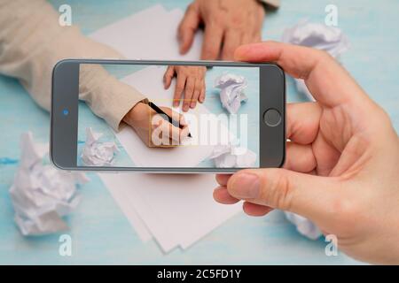 Pen in man's hand. White sheet of paper. Signing document. Photo smartphone. Smartphone in hand. Signature on screen. Stock Photo