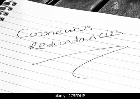 CORONAVIRUS REDUNDANCIES written on lined paper Stock Photo
