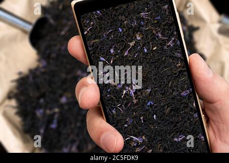 Black tea on smartphone screen. Natural food product. Stock Photo