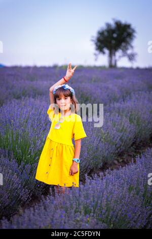 Cute girl in yellow dress in lavender field Stock Photo