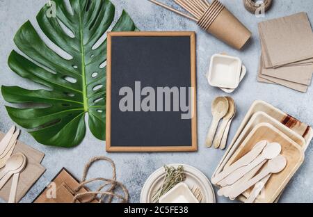Eco craft paper and bamboo tableware. Recycling or eco-friendly Paper cups, dishes, platesand, wooden cutlery, monstera leaves, mock up, Top view Stock Photo