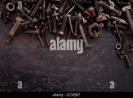 old nuts, screws and nails greasy and dirty heavily rusted lie on a metal dark background Stock Photo