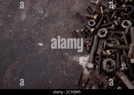 old nuts, screws and nails greasy and dirty heavily rusted lie on a metal dark background Stock Photo