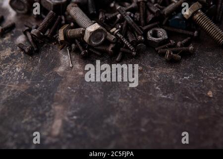 old nuts, screws and nails greasy and dirty heavily rusted lie on a metal dark background Stock Photo