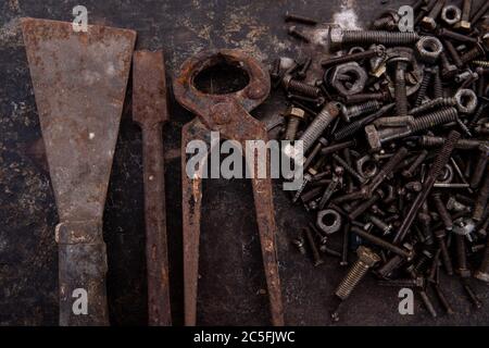 old nuts, screws and nails greasy and dirty heavily rusted lie on a metal dark background Stock Photo