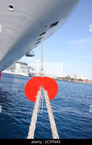 Bow of Cruise Ship tied up to dock with white rope & red shield. Stock Photo