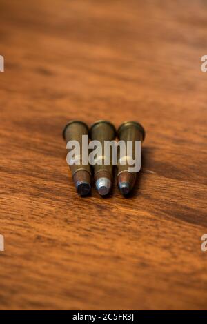 Three bullets laying on wooden background Stock Photo
