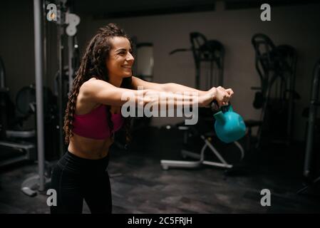 Beautiful smiling woman with curly hair working out with kettleb Stock Photo