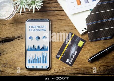 Financial Planning background Concept. Top view of Financial Planing application on smartphone with business reports graph chart, credit card, and bus Stock Photo
