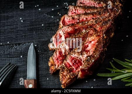 Barbecue dry aged rib of beef with spice, close-up on black wooden background Stock Photo