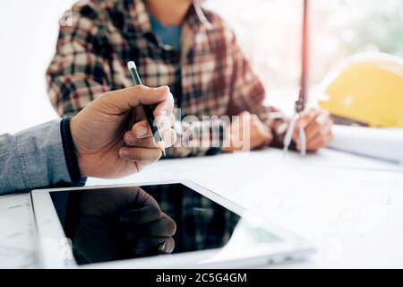 Male engineering using digital tablet with architectural plan on desk. Stock Photo