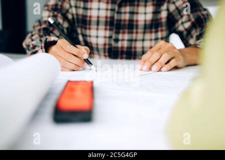 Architect working and examining blueprints for new project in new modern office. Stock Photo