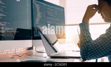 Male programmers are stressed at the office while working analyzing on desk in code at office room. Stock Photo