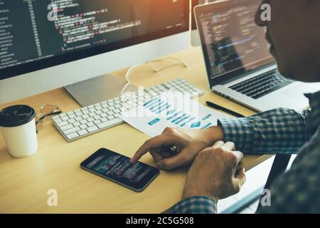 Software developers are using mobile phones to read the code. Stock Photo
