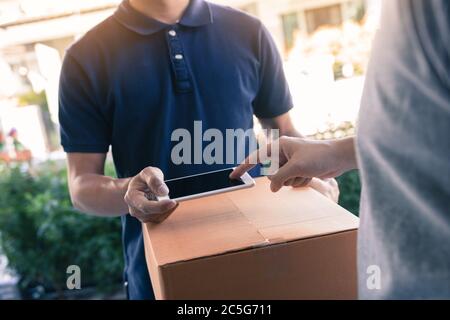 Close up of hand asian man using smartphone pressing screen to sign for delivery from the courier at home. Stock Photo