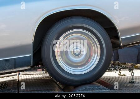 A car running at full speed on a dynamometer. The car is not moving but the wheel is spinning full speed. Closeup side view, in the shadows outdoors. Stock Photo