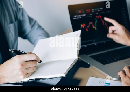 Investors are using a pen to writing data for the company that is analyzing the shares with colleagues at the office. Stock Photo