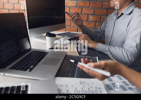 Two software developers are analyzing together about the code written into the program on the computer. Stock Photo