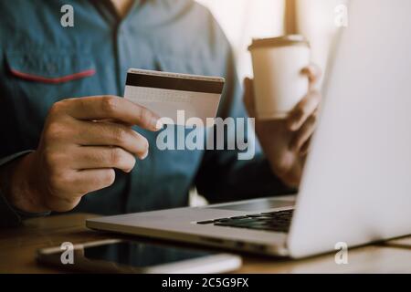 Men's hands are holding smart phones and drinking coffee with shopping online concept. Stock Photo