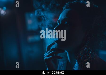 Young smoking woman dark night portrait. Blue tint. Stock Photo
