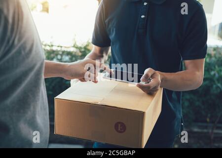Close up of hand asian man using smartphone pressing screen to sign for delivery from the courier at home. Stock Photo