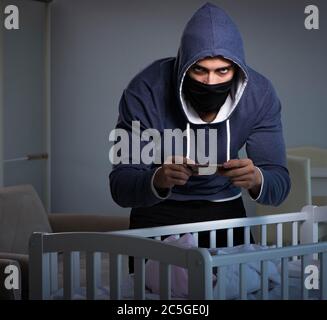 The criminal stealing baby in human child traficking concept Stock Photo