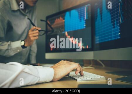 Two business stock brokers stress and looking at monitors displaying financial information. Stock Photo