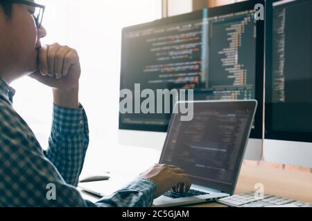 Man programmers are stressed and hand holding nose with headache at the office while working analyzing on desk in code at office room. Stock Photo