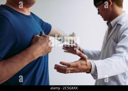 Asian male physical therapist descent working and helping to protect the hands of patients with patient doing stretching exercise with a flexible exer Stock Photo
