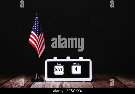 The American Flag draped on a Flag Stand next to a calendar showing JULY 4 american independence day Stock Photo