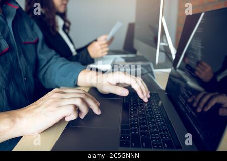 Two partnerships developing programming and coding technologies working on laptop and analyzing together. Stock Photo