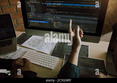 Two software developers are analyzing together about the code written into the program on the computer. Stock Photo