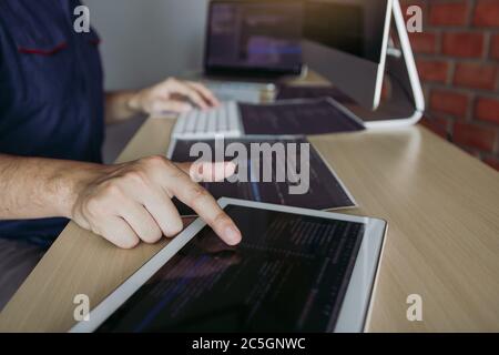Software developer is pointing to the paper working and analyzing together the code written into the program on the computer. Stock Photo