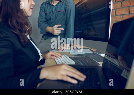 Two software developers are analyzing together about the code written into the program on the computer. Stock Photo