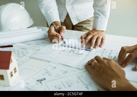 Architects engineer working with blueprints on table and discussing project together at the meeting in the office. Stock Photo