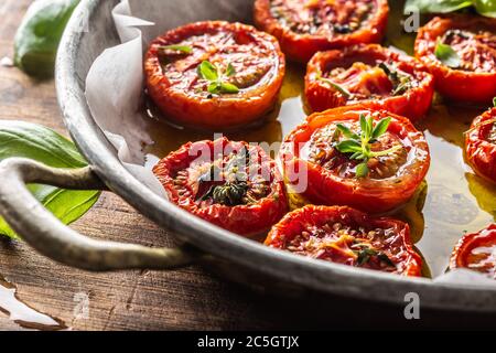 Roasted tomatoes with olive oil thyme oregano and basil in pan Stock Photo