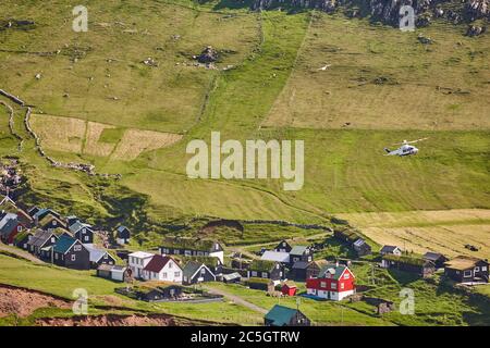 Helicopter flying over mykines village in Faroe islands. Denmark Stock Photo