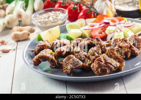 Traditional pork satay with peanut sauce and vegetables. Indonesian and Malaysian food. Stock Photo