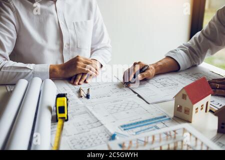Architects engineer working with blueprints on table and discussing project together at the meeting in the office. Stock Photo