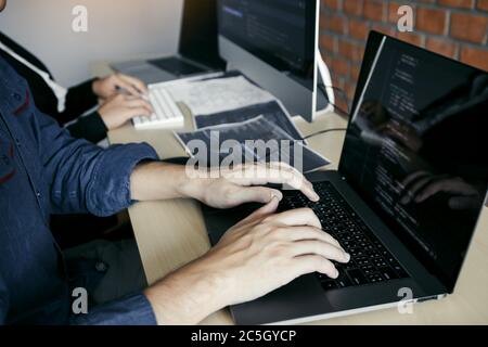 Two partnerships developing programming and coding technologies working on laptop and analyzing together. Stock Photo