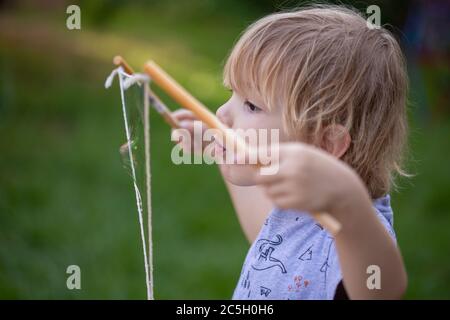 Young preschool boy blowing giant rainbow bubbles in a backyard setting Stock Photo