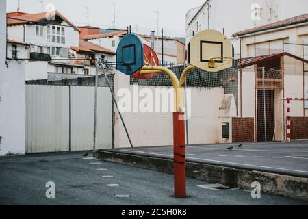 Empty school asphalt playground in the backyard with three color baskets for basketball and part for handball in background Stock Photo