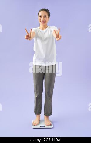 Happy woman smiling on weighing scales at gym. Trainer with female client  checking fitness progress. Personal training programme for weight loss  Stock Photo - Alamy