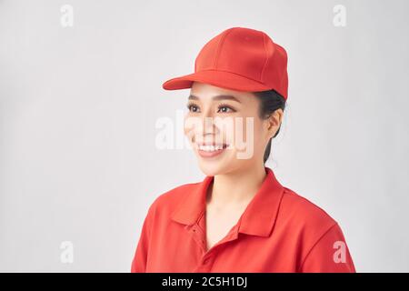 Smiling delivery woman in red uniform standing with arm crossed - isolated on white background Stock Photo